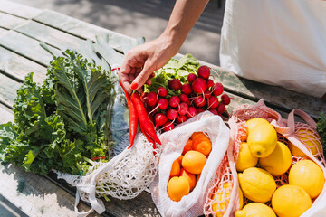 Woman holding red chilies and buying fresh vegetables in market