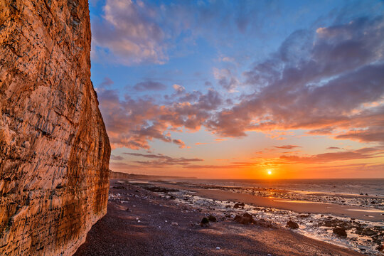 Chalk cliffs near coastline at sunset under cloudy sky - Powered by Adobe