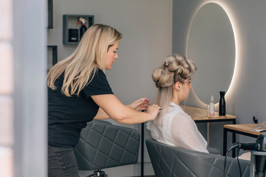 Hairdresser combing woman's hair in salon