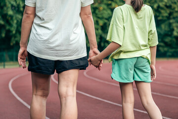 Mom and daughter hold each other's hands in the stadium.