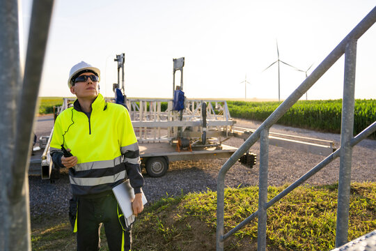 Engineer wearing hardhat examining wind turbines