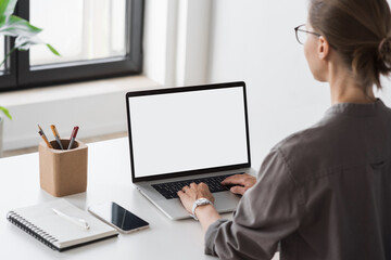 Young woman using laptop computer with blank empty mockup screen. Businesswoman working at home. Freelance, student lifestyle, e-learning, shopping online, web site, technology concept