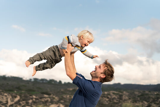 Happy father holding son under cloudy sky