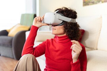 Smiling woman wearing virtual reality headset sitting at home