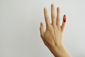 Female hand with red blood, little finger is bleeding profusely. Woman injured her little finger at...