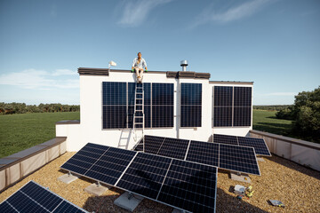 Rooftop of a private house with solar power station on it, man sitting on a top and enjoys his...