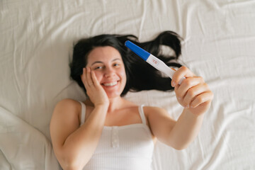 happy woman showing positive pregnancy test