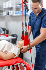 Female patient hanging on suspensions at rehabilitation center.