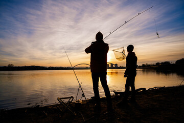 Father and son are fishing on winter day. River fishing.