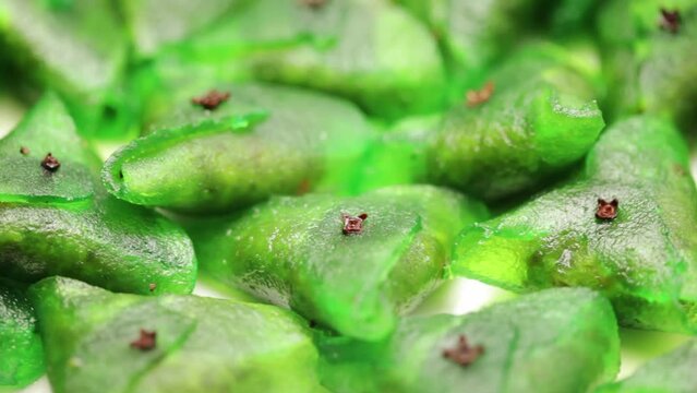  Close-up of Indian sweet "Paan petha" revolving on a white ceramic plate.