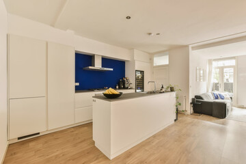 a kitchen and living room in a modern apartment with white walls, wood flooring and bright blue accent wall