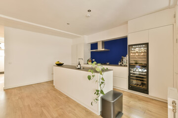 a kitchen and dining area in a house with white walls, hardwood flooring and blue accent on the wall