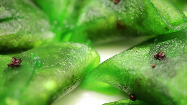 Close-up of Indian sweet "Paan petha" revolving on a white ceramic plate.