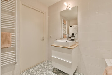Fototapeta na wymiar a bathroom with white walls and floor tiles on the wall there is a sink, mirror and towel rack in the room