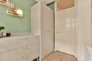 a room with green walls and white furniture on the left side of the room, there is an open door that leads to a