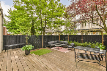 an outdoor living area with wood decking and black privacy fenced in the back yard, surrounded by trees