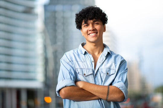 smiling young guy in city with arms crossed
