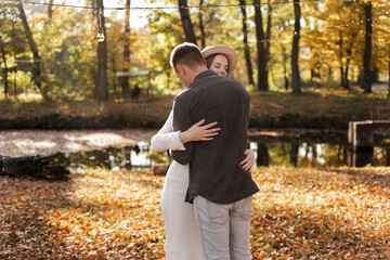Young stylish couple lovers are hugging in the autumn park. Lovely romantic moment between man and woman in love. Happy family. Love, youth, happiness concept.