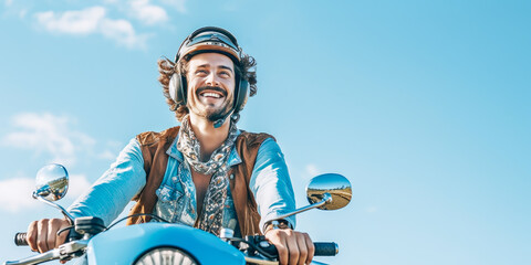 Young handsome cheerful smiling man have fun ride motorbike on clear blue sky background. Concept of moto transports, delivery, travel and summer holiday. Banner size, copy space