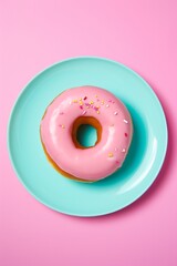 A delightful pink donut resting on a bright blue plate tantalizes the senses, evoking a feeling of warmth and joy that only a sweet dessert can bring