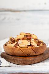 Brazil nut in wood bowl. Brazilian nuts peeled on white wood background