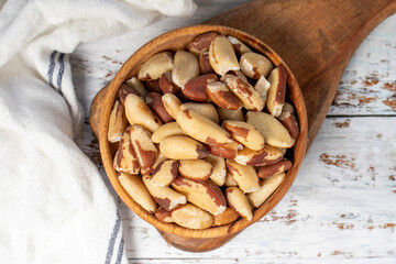 Brazil nut in wood bowl. Brazilian nuts peeled on white wood background. Top view
