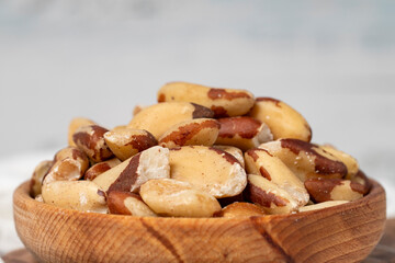 Brazil nut in wood bowl. Brazilian nuts peeled on white wood background. Close up