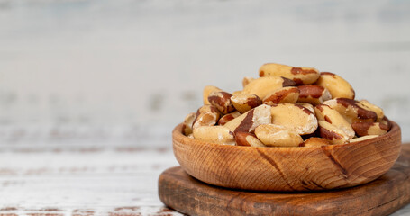 Fototapeta na wymiar Brazil nut in wood bowl. Brazilian nuts peeled on white wood background. Copy space. Empty space for text