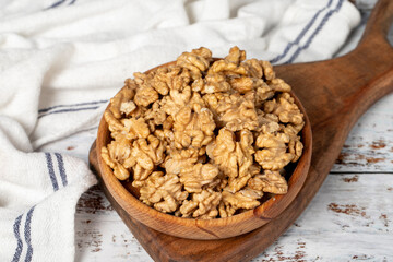 Walnut in wood bowl. Walnut peeled on white wood background