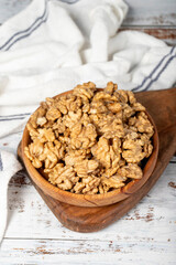 Walnut in wood bowl. Walnut peeled on white wood background. Close up