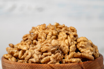 Walnut in wood bowl. Walnut peeled on white wood background. Close up
