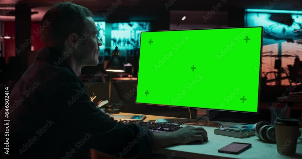 Poster portrait of creative man sitting at his desk using desktop computer with mock-up green screen. male 