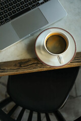 Laptop and coffee on table in cafe, top view