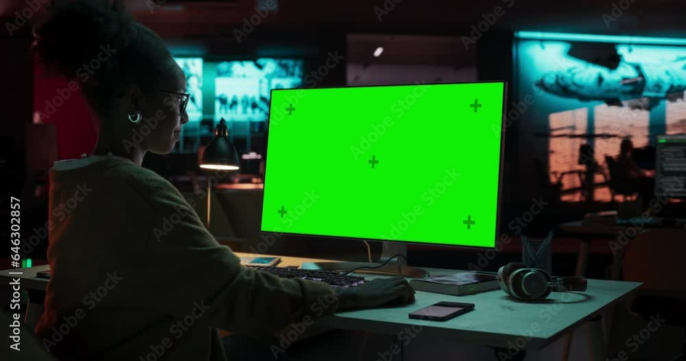 Poster portrait of creative black woman sitting at her desk using desktop computer with mock-up green scree