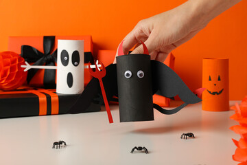 Gift boxes, paper halloween characters and hand on orange background