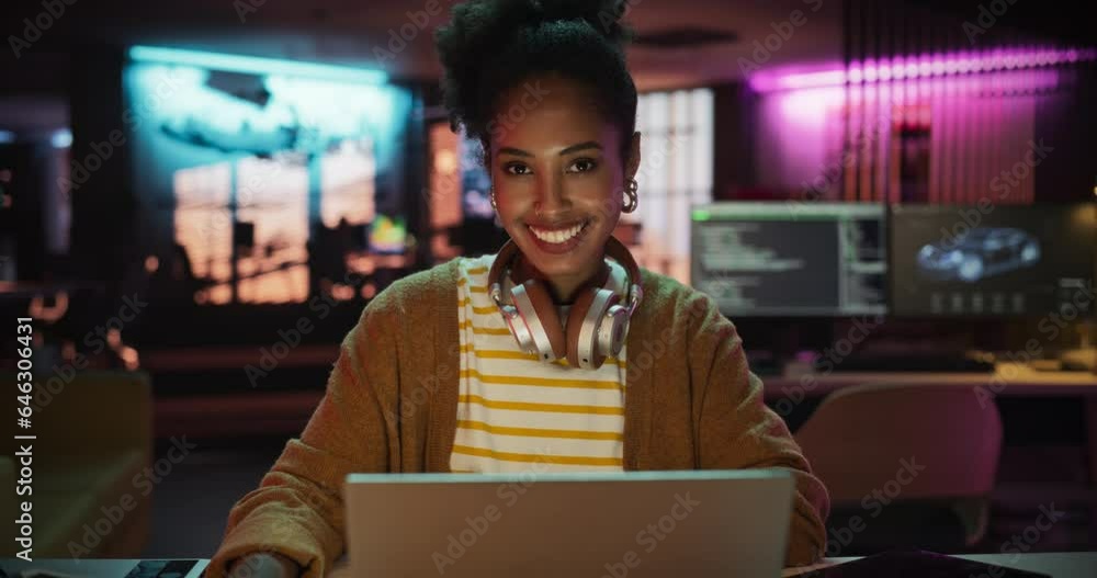 Fototapete portrait of a black smiling female, using laptop computer, looking at camera and smiling in a creati