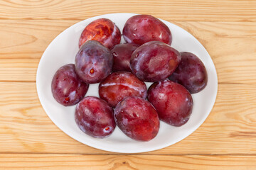 Fresh washed plums on the dish on the rustic table