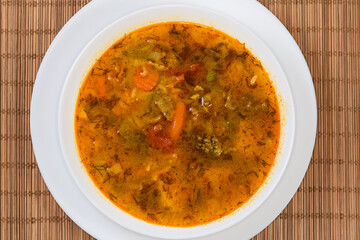 Vegetable red soup in bowl on place mat, top view