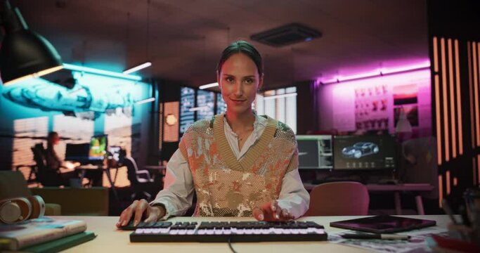 Portrait of a Female Software Developer Writing Code in a Creative Office with Neon Lights. Young Woman Focused on Typing on Keyboard and Working on Desktop Computer. Point of View of Screen Monitor