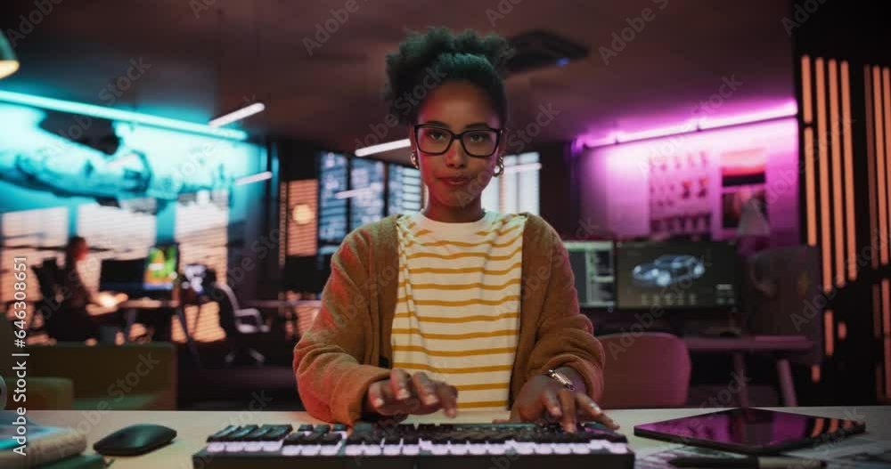 Aufkleber Portrait of a Black Female Developer Writing Code in a Creative Office with Neon Lights. Young Woman Focused on Typing on Keyboard and Working on Desktop Computer. Point of View of Screen Monitor