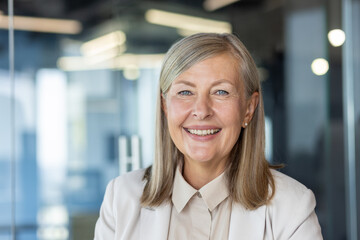 Close-up portrait of mature gray-haired business woman, senior adult woman smiling and looking at...