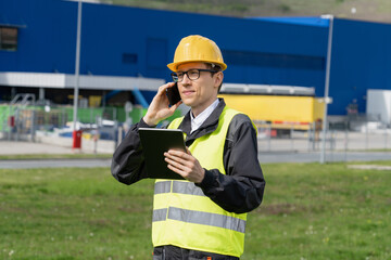 Logistician with phone and digital tablet on a background of logistic center.