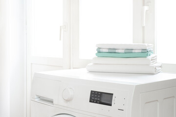 Washing machine and clean laundry stack on white window background