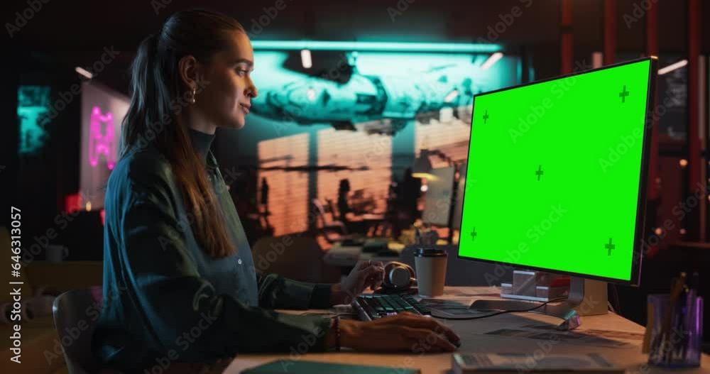 Poster zoom in portrait of young woman sitting at her desk using desktop computer with mock-up green screen