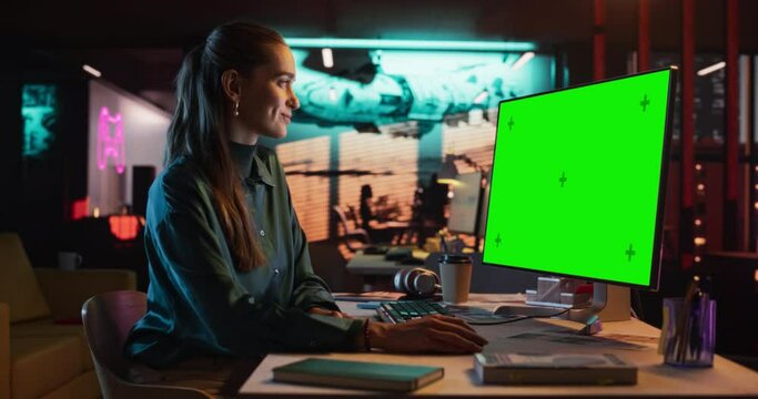Portrait of Female Working in Creative Agency Office, Checking Data and Sending E.Mails. Successful Specialist Using Desktop Computer with Green Screen Mock Up Display During Night