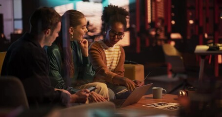 Group of Young Successful Businesspeople Making a Team Meeting in Conference Room in Creative Agency. Excited Diverse Team Using Laptop Computer, Discussing a New Corporate Strategy. Evening at Work
