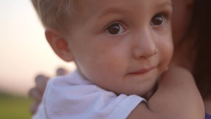 mother holding her son in her arms in the park. baby son hugs mom big in the park in nature. happy family kid dream concept. mom take care of her son baby hugs him holds sun him in her arms in park