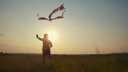 boy running with a kite. happy family kid dream concept. boy son running with his back sunset...