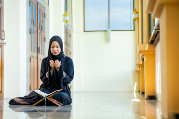 The image of an Asian Muslim woman in the Islamic religion in hijab in black  color. reading the...