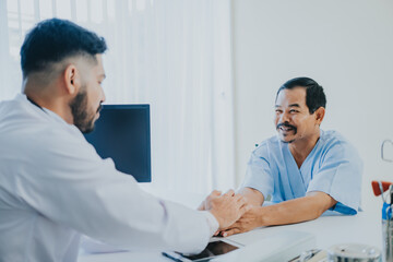 Fototapeta premium The Asian Muslim man doctor was sitting at the patient's examination table and was examining and talking about the patient with a smiling and worried face in hospital.